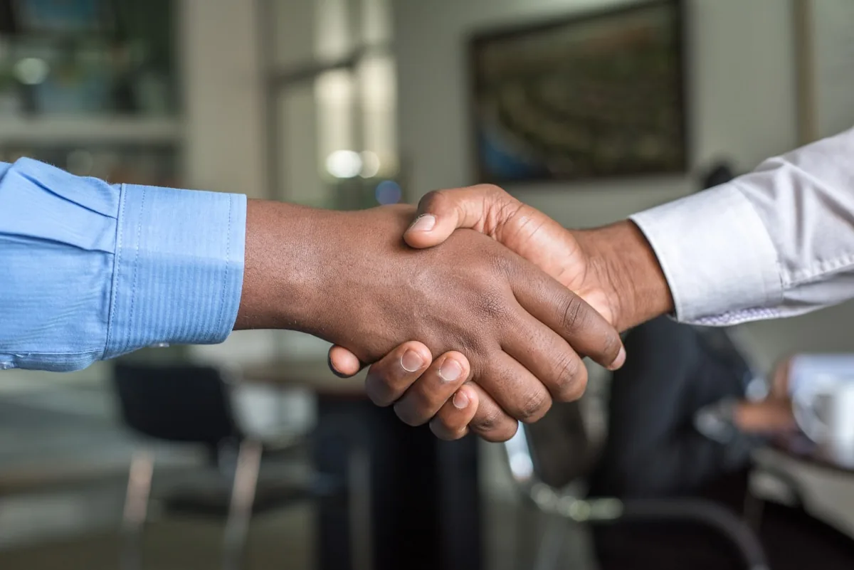 Two business professionals shaking hands in a modern office